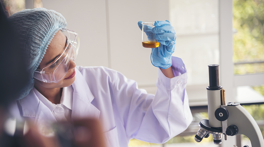 Female chemistry student in a lab studying a liquid in a container